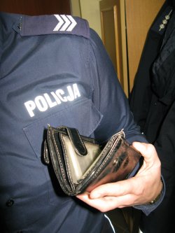 Część sylwetki policjanta i czarny portfel trzymany w ręku