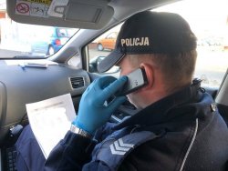 policjant siedzi w radiowozie i dzwoni z telefonu komórkowego