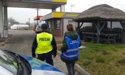 pracownicy inspekcji wraz z policjantem zmierzający w stronę sklepu przy stacji benzynowej